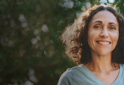 Woman representing an RMS patient stands in front of an outdoor background
