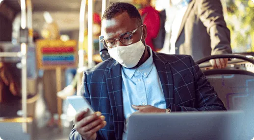Man representing an RMS patient wearing glasses and a mask uses a cell phone and laptop